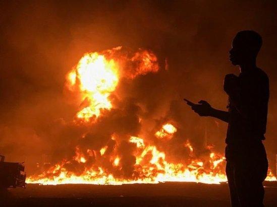 A man stands with his phone in front of flames rising from a pipeline explosion in Abula-Egba, Lagos, Nigeria January 19, 2020. REUTERS/Seun Sanni
