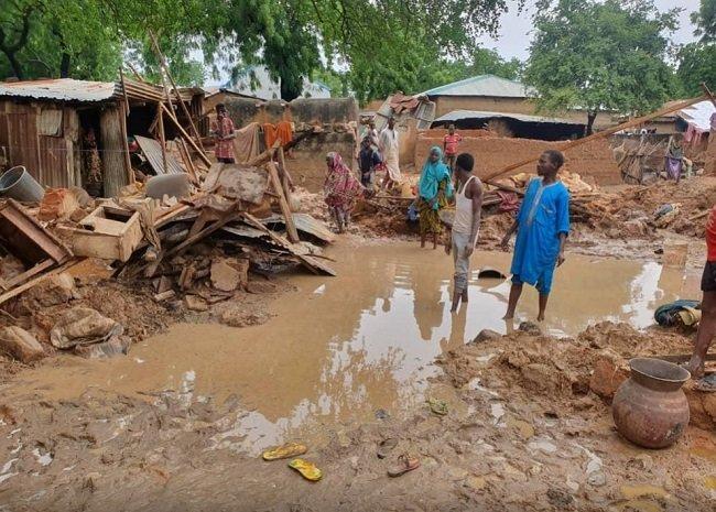 People stand outside after their houses were destroyed following heavy rains in Kebbi state, Nigeria in this handout picture taken September, 2020. SEMA/Handout via REUTERS