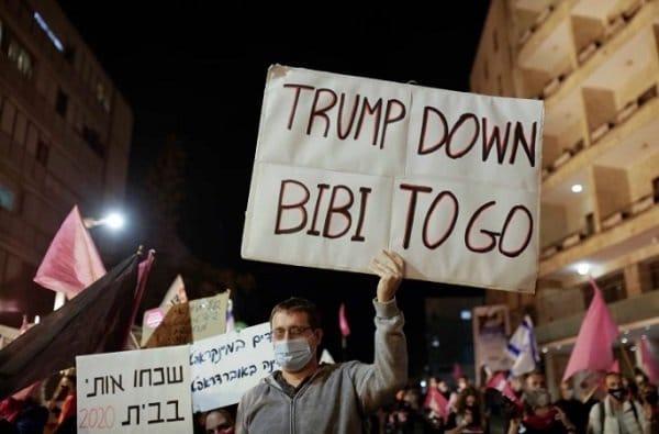 An Israeli protester holds a sign against Netanyahu