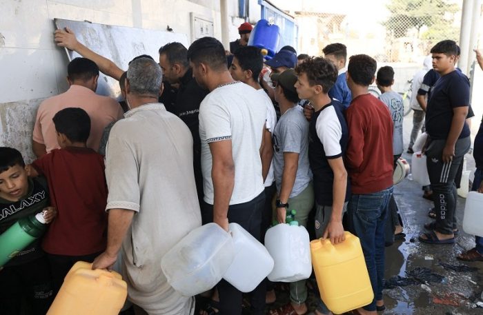 Palestinians queue to fill containers with water in Khan Yunis in the southern Gaza Strip on October 14, 2023, as bombs fall on Gaza for an eighth straight day [Mahmud Hams/AFP]